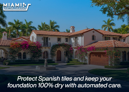 A wide, stunning shot of a historic Coral Gables home with Spanish barrel tile roofs, with clean gutters diverting heavy rain smoothly away from immaculate stucco walls.