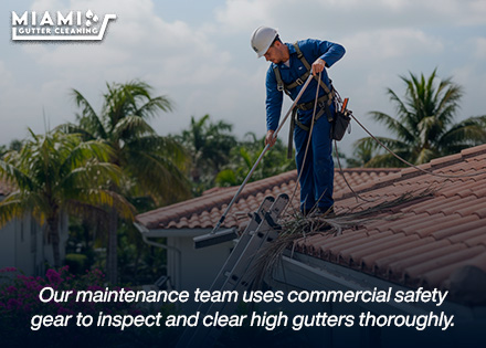 A technician from our maintenance division using professional ladder stand-offs and safety gear to clear a roofline safely.